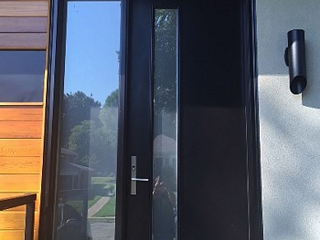 Modern panel window with black custom entry steel door by FORHOMES Ltd.