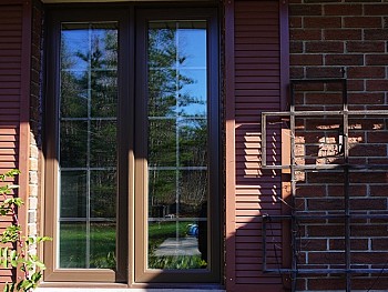 Contemporary vinyl windows with brown pain on the outside and false shutters/ grilles